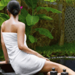 woman in a towel seated by the edge of a tropical pool (radiant recharger)